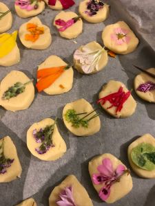 Edible flowers being attached to biscuits with egg white 